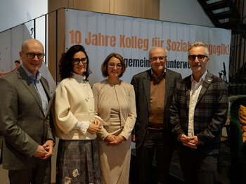 Bild v.l.n.r.: Landesrat Wolfgang Fürweger, Caritasdirektorin Andrea Schmid, 
Johanna Harb, Leiterin des Kollegs für Sozialpädagogik, Festredner Reinhard Haller, Psychiater und Autor und Caritasdirektor Kurt Sonneck. 5 Personen stehen vor einerm Jubiläumsplakat