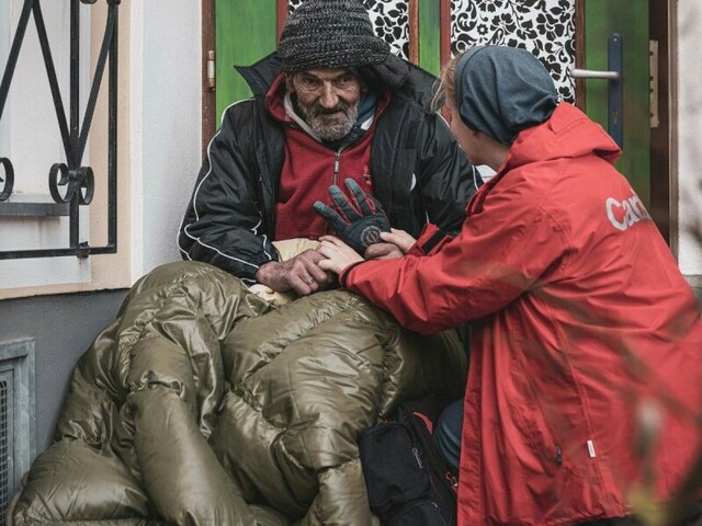 Obdachdachloser im Schlafsack mit Street Workerin