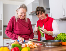 Eine alte Frau und eine Betreuerin beim Kochen in der Caritas Altenpension.