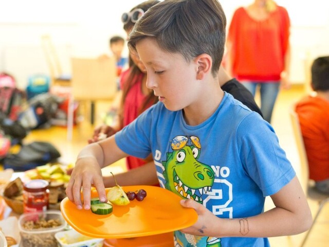 Jause in einem Lerncafé  Ein Junge nimmt sich Essen von einem Buffet