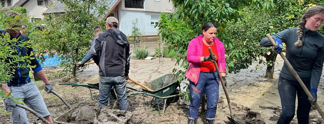 Freiwillige mit Schaufeln, sie entfernen Schlamm nach Hochwasser