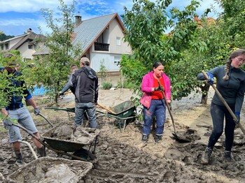 Freiwillige mit Schaufeln, sie entfernen Schlamm nach Hochwasser