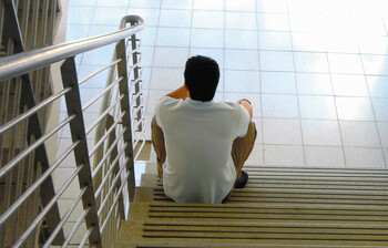 Ein Mann sitzt alleine auf einer Treppe.